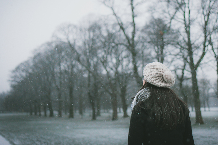 Jonge vrouw wandelt buiten in de sneeuw.